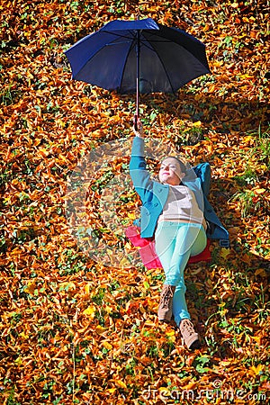 Young girl relaxing with umbrella in autumnal park