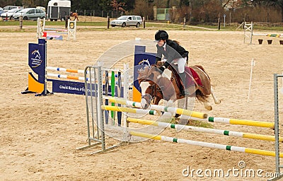 Young girl on the horse at jumping competition