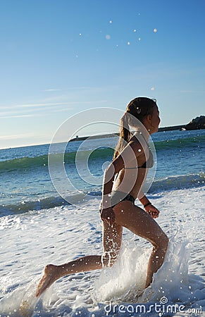 Young girl running in the surf.