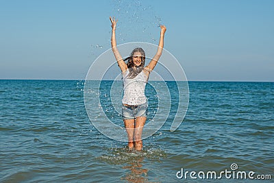 Young girl splashing the water in the sea