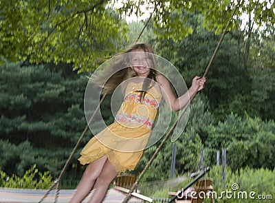 Young girl standing on tree swing