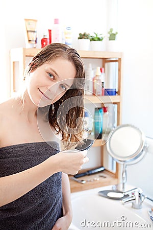 Young girl taking care of her hairs in a bathroom