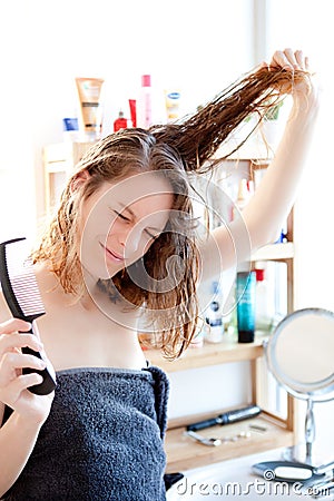 Young girl taking care of her hairs in a bathroom