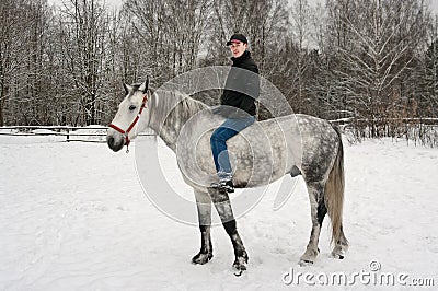 The young guy sits on is light grey horse