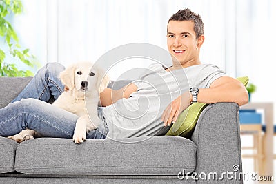 Young guy sitting on couch with a puppy at home
