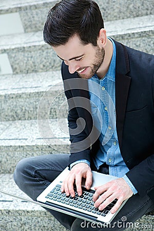 Young guy smiling and using laptop