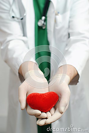 Young handsome doctor holding heart in hand