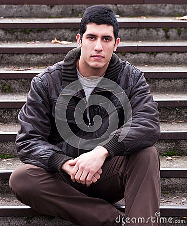 Young handsome man sitting on stairs outside