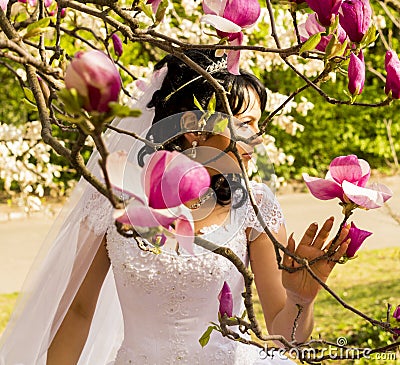 Young happy bride smells flowers magnolia outdoors