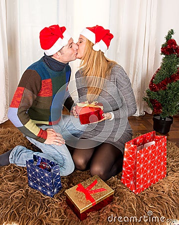 Young Happy Couple Kissing on rug at Christmas
