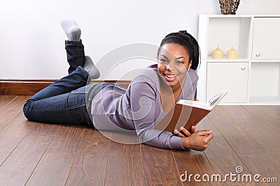 Young happy female student reading book at home
