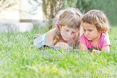 Young happy kids, children reading books on natural backgrou