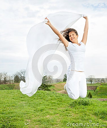 Young happy woman jumps and holding a white piece of cloth in th