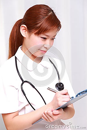 Young Japanese nurse fills medical chart