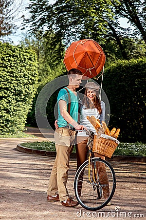 Young and joyful couple having fun in the park with bicycle and