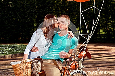 Young and joyful couple having fun in the park with bicycle and