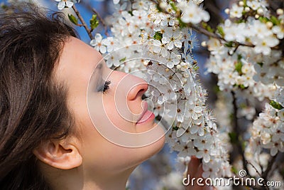 Young lady smells a blooming tree