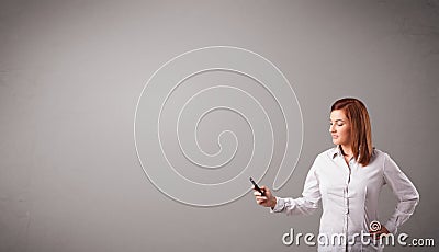 Young lady standing and holding a phone with copy space