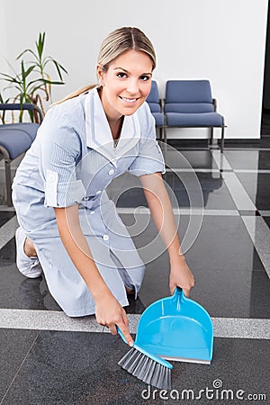 Young maid sweeping the floor