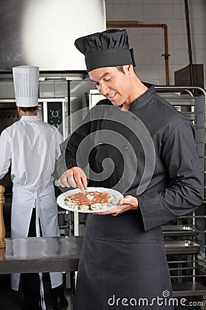 Chef Garnishing Dish In Kitchen