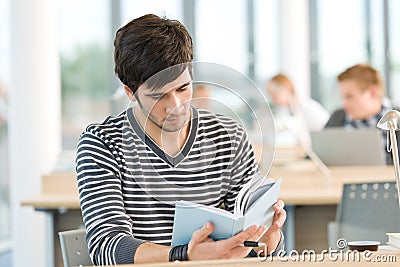 Young male student read book in classroom