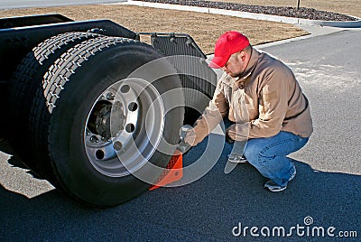 Young male truck driver chocking wheels for safety