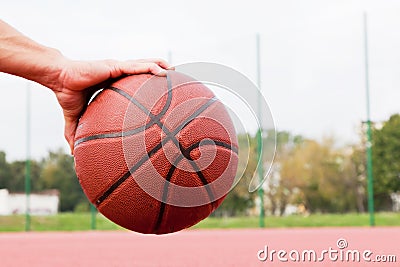 Young man on basketball court. Sitting and dribbling with ball