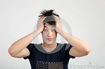 Young man with crazy hair holding his head confused. Bad hair day.