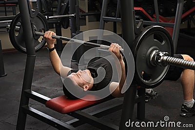 Young man doing bench press workout in gym