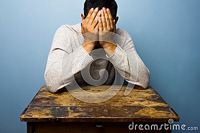 Young man face palming at desk