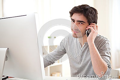 Young man having a call in front of computer