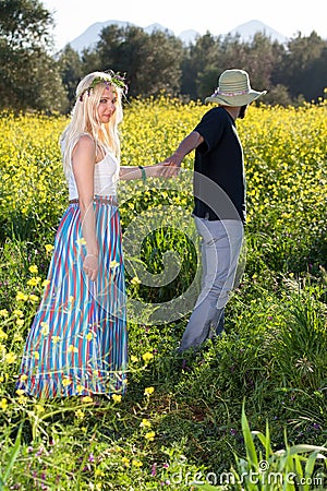 Young man leading his girlfriend through rapeseed.