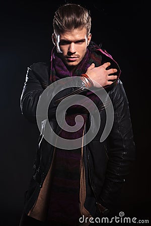 Young man in leather jacket adjusting his scarf