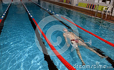 Young man lies on water and relax in swimming pool.