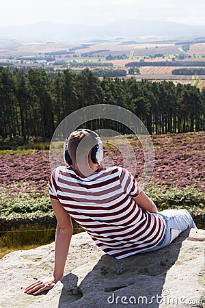 Young Man Listening To Music In Countryside On Headphones