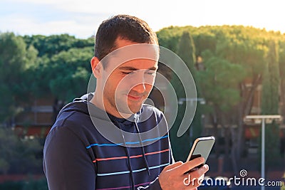 Young man with mobile phone on trees background, outdoor