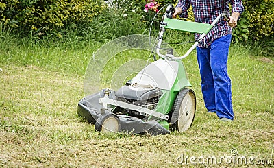 Young man mowing the lawn with a lawnmower