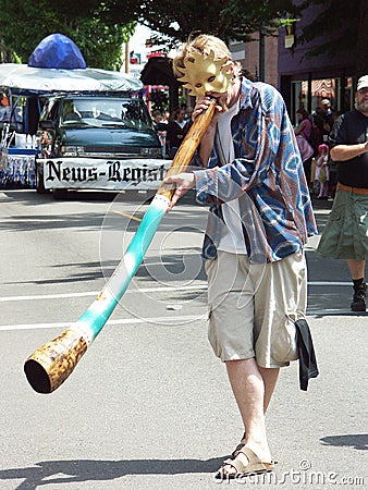 A young man in a parade blowing an Australian horn