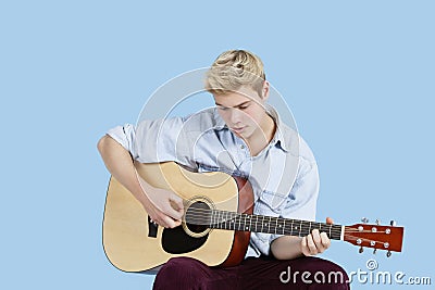 Young man playing guitar over blue background