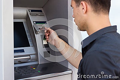Young man put his credit card at the ATM