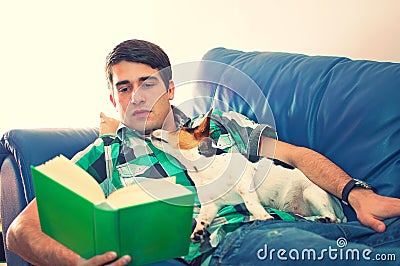 Young Man Reading A Book With His Dog On A