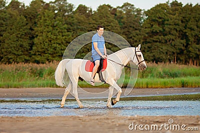 Young man riding a horse at sunset on the beach. Man with a hors