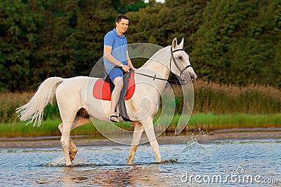 Young man riding a horse at sunset on the beach. Man with a hors