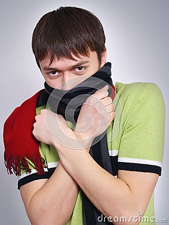 Young man in a scarf heats hands