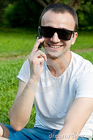 Young man speaks on the phone on the grass