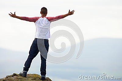 Young Man Standing On Rock With Outstretched Arms