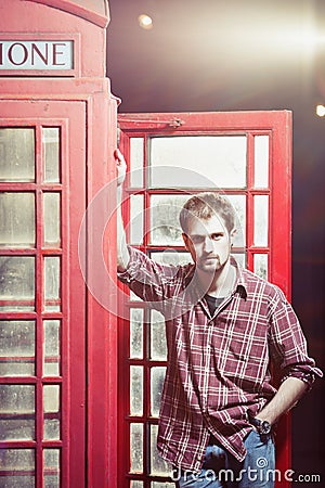 Young man standing at telephone box