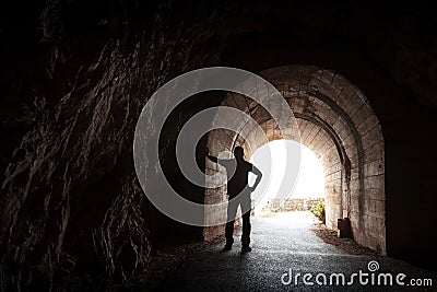 Young man stands relaxed in dark tunnel