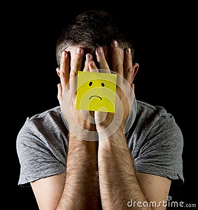 Young man suffering depression and stress alone with sad face post it note