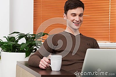 Young man using laptop and drinking tea.